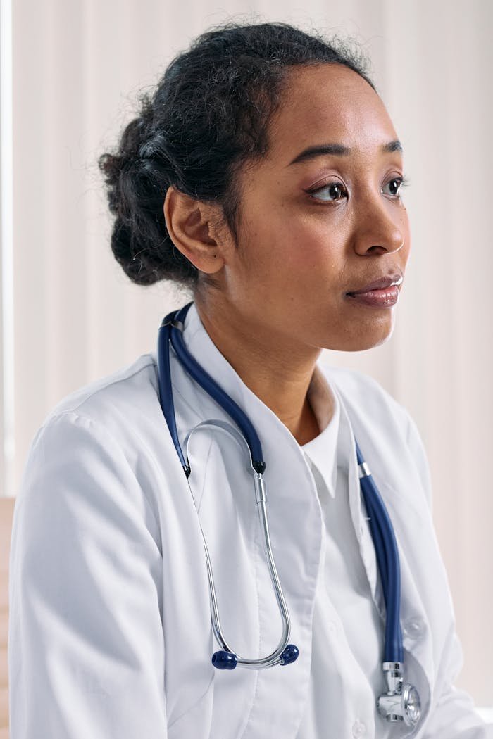 Close-up of a focused female doctor in a white coat with a stethoscope indoors.