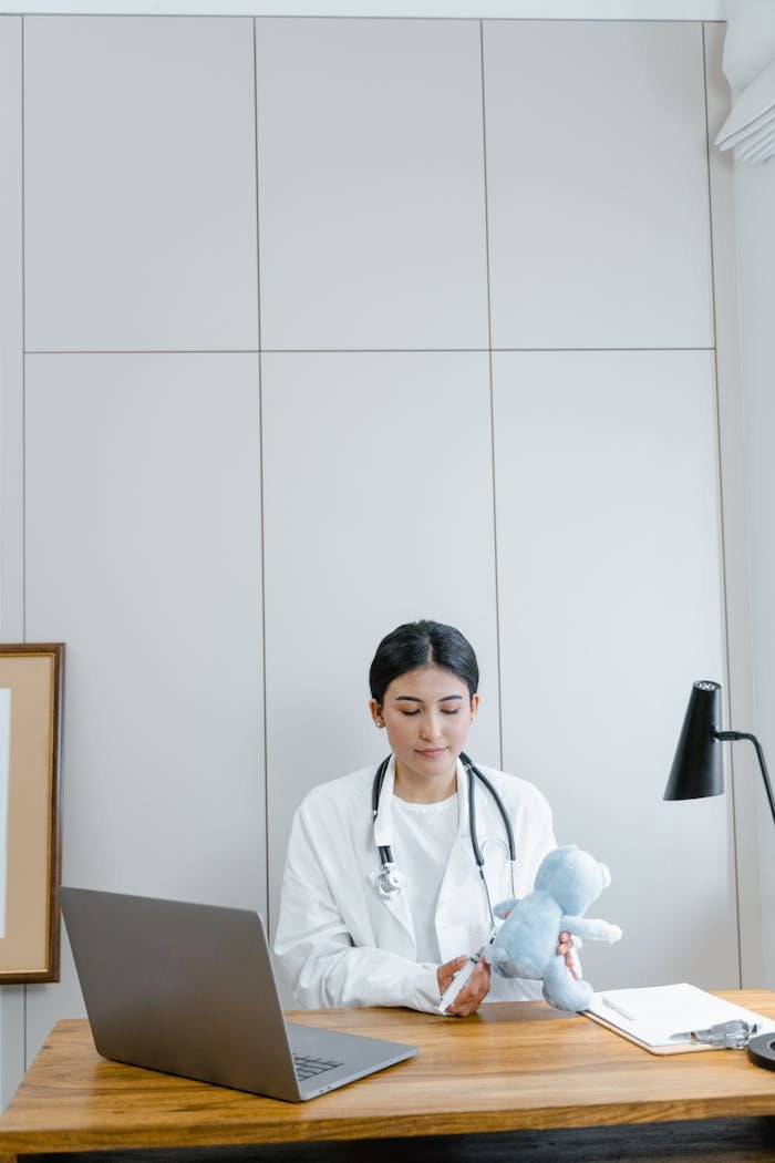 services-03 Female doctor in medical office examining a blue stuffed toy, symbolizing pediatric care.